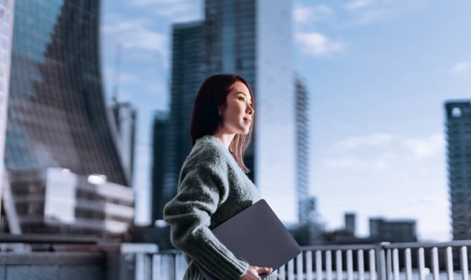 Woman looking out over the skyline holding a folder of her work